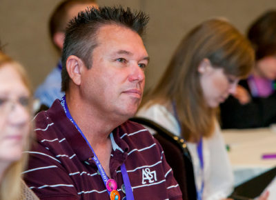 A parent looks upset at a curriculum meeting.