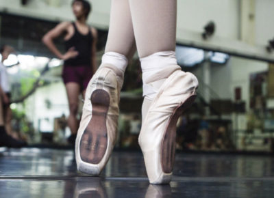 A pair of ballet slippers on point in a studio.