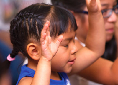 A child raises her hands in worship at church.