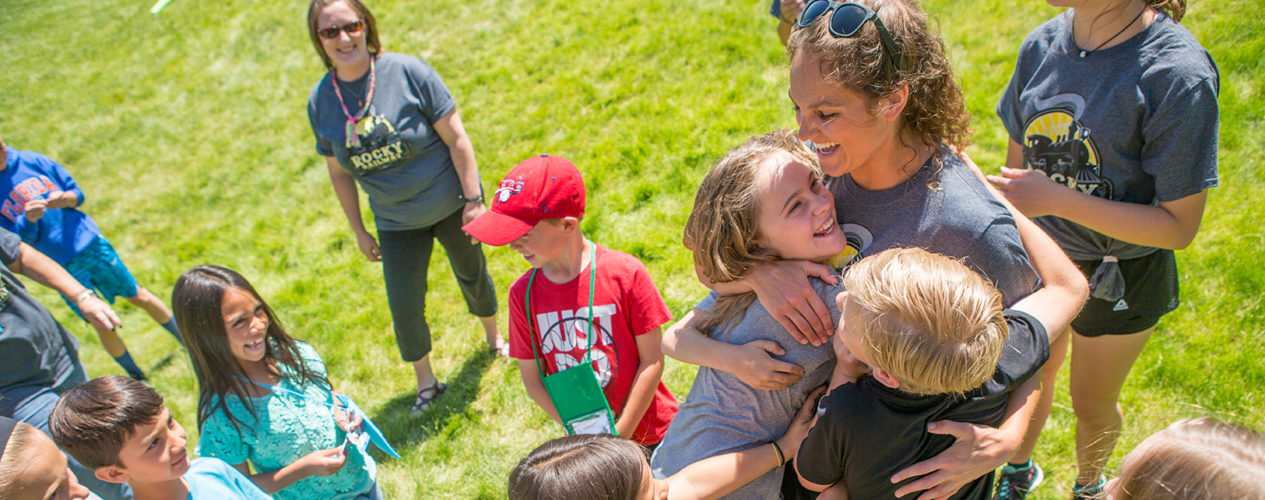 A VBS leader hugs a bunch of children.