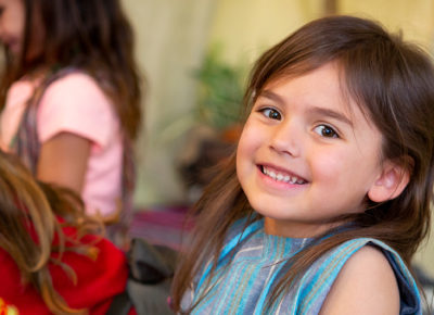 A preschool girl smiles during a lesson on peer pressure.