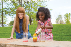 Two girls doing a science experiment outdoors.