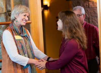 Greeter warmly welcomes wife to church as her husband follows.