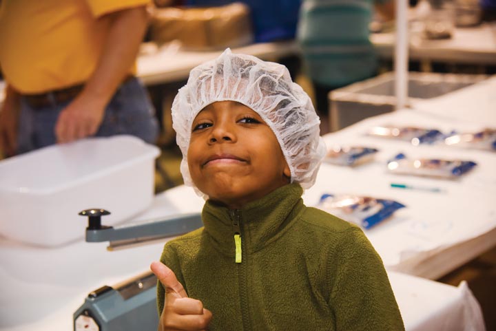 Little boy gives thumbs up and a smiling in his hairnet.