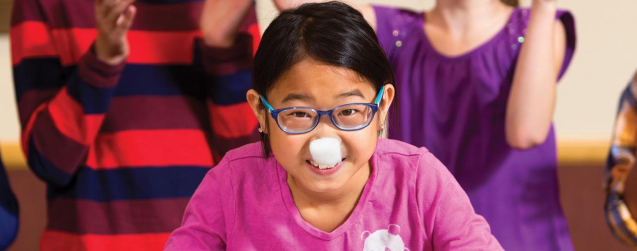 A girl with a cotton ball on her nose plays a game in her children's ministry class.
