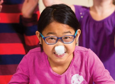 A girl with a cotton ball on her nose plays a game in her children's ministry class.