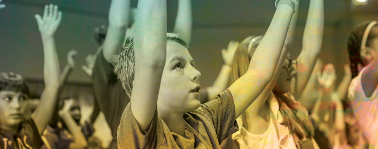 Preteen boy with his hands raised up towards the Lord as he sings.