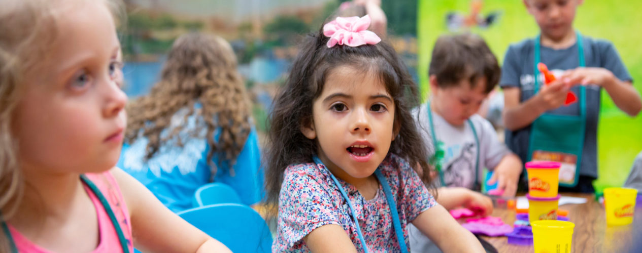 A preschool girl sitting at a table with Play Doh.