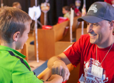 A male volunteer gives a young boy a fist bump.