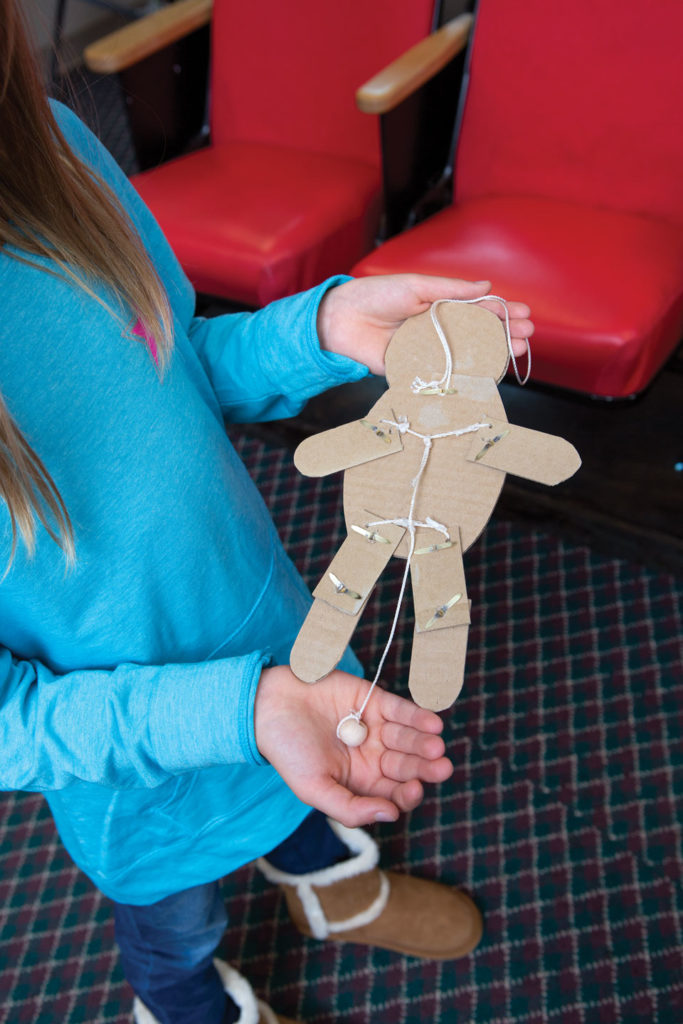 Preteen girl showing the assembly side of a dancing baby craft.