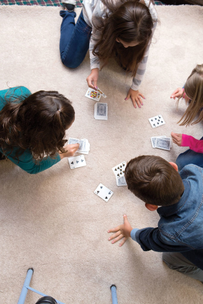Four children playing a game with cards.