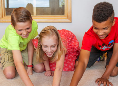 Three preteens playing a teamwork-centered game inside.