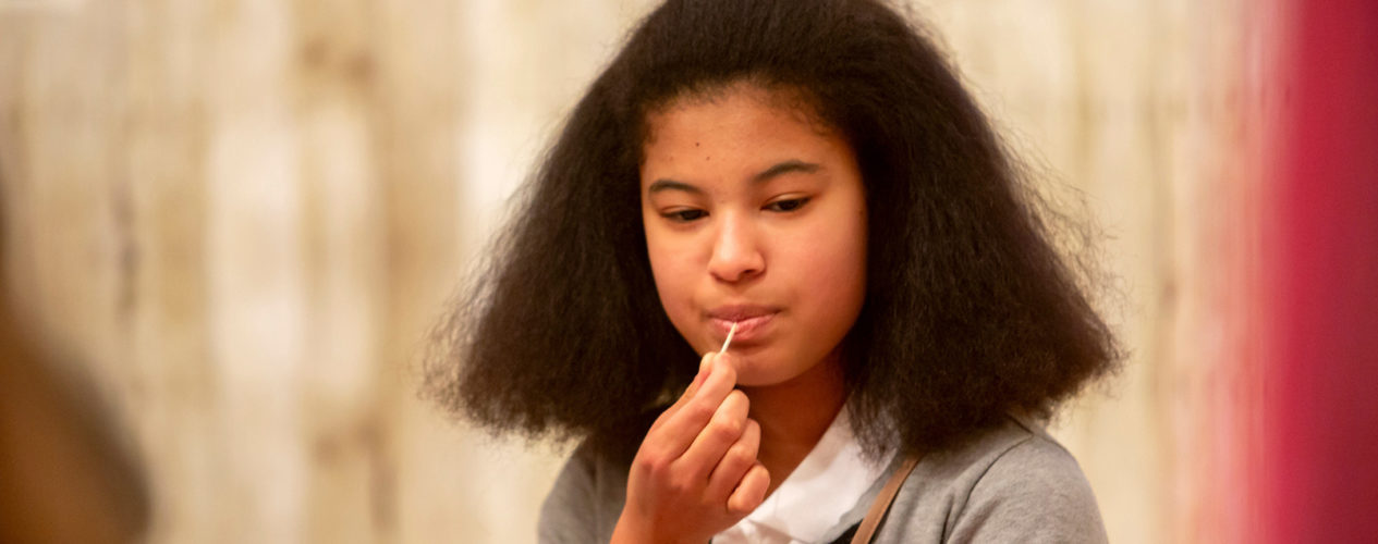 Preteen girl ponders something in her mind as she tastes a toothpick.