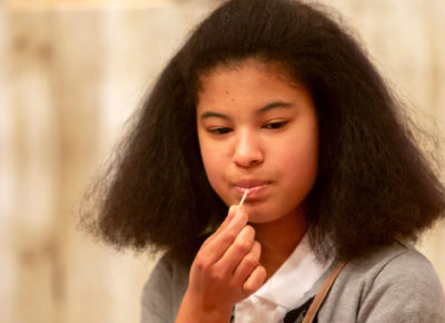 Preteen girl ponders something in her mind as she tastes a toothpick.