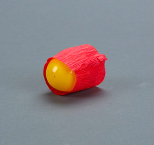 A yellow plastic egg wrapped with red crepe paper.
