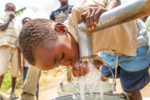 A young boy drinking form a faucet.