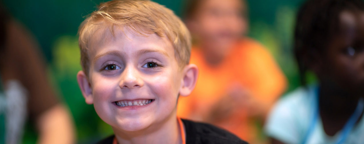 An elementary boy smiles straight at the camera.