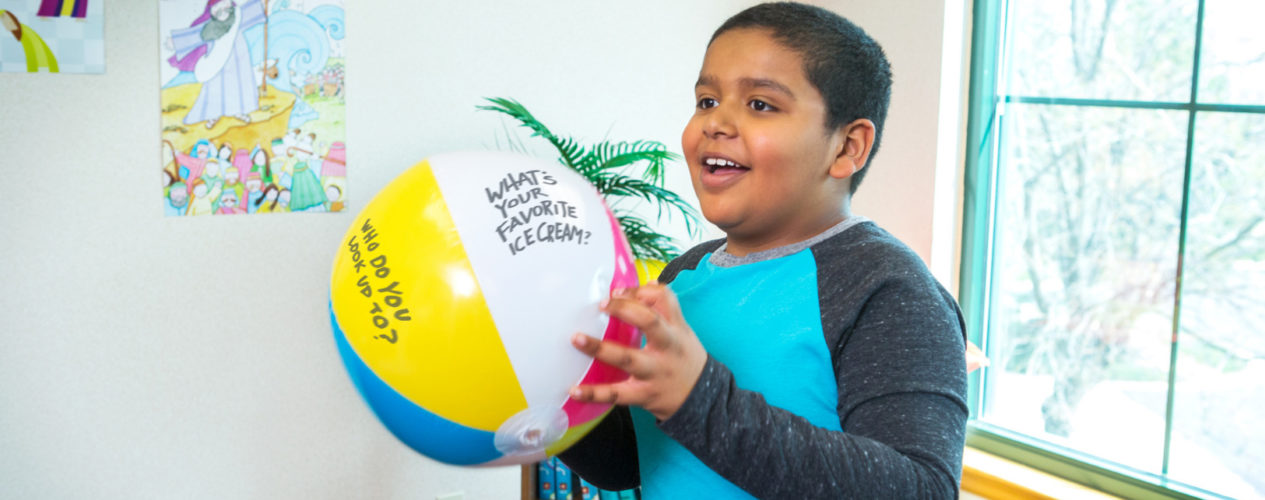 A preteen boy participating in a name learning game with a beach ball.