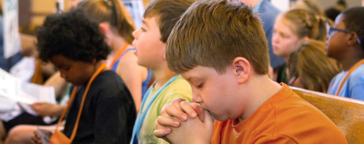 An older elementary boy prayers for the president on President's Day.