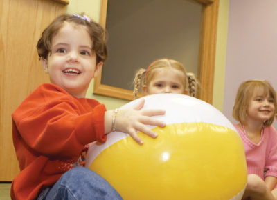 A group of preschoolers playing a game with a beach ball.