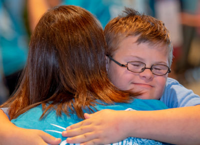 A woman volunteer hugs a boy with special needs.