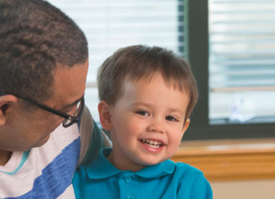 A male volunteer holds a smiling toddler.
