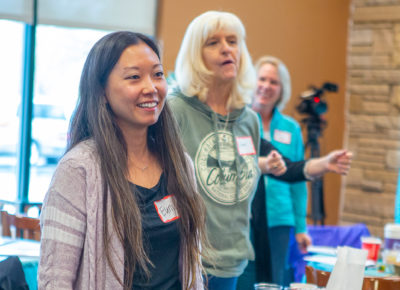A woman is standing and smiling at a leadership retreat.