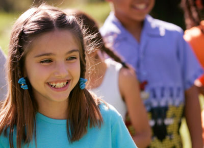 girl in blue shirt smiling outside
