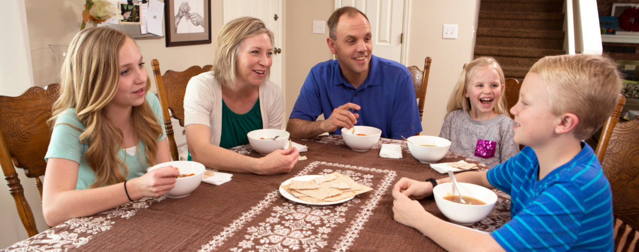 family seated around dinner table eating and talking
