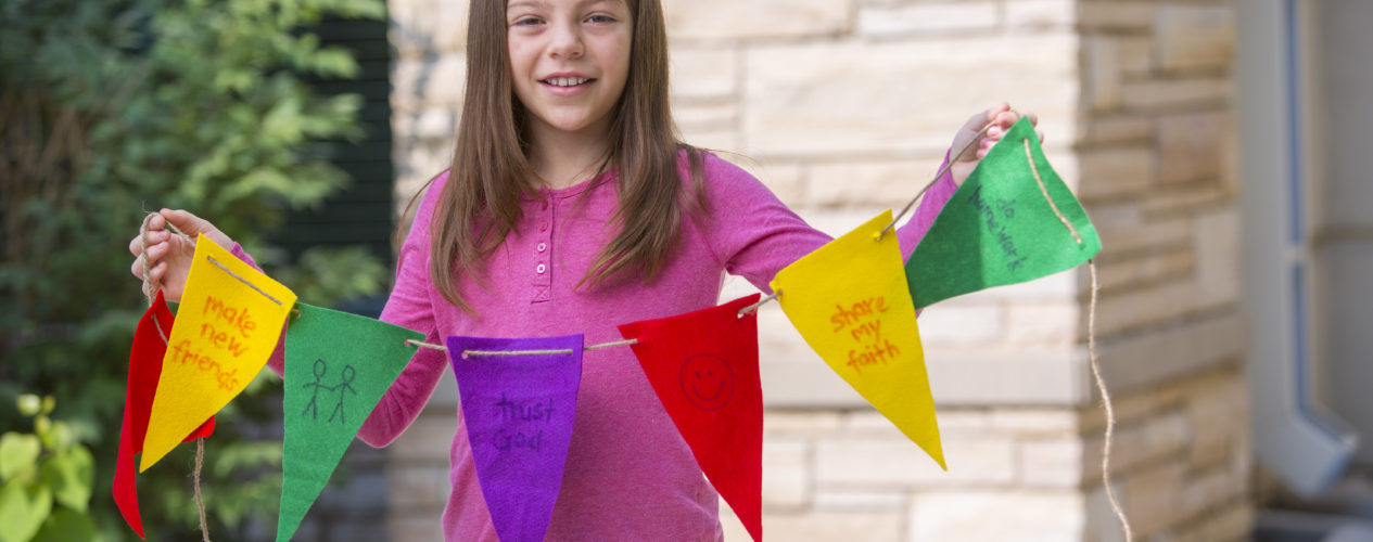 girl holding up string of pennants