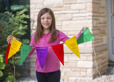 girl holding up string of pennants