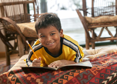 boy smiling while writing in book