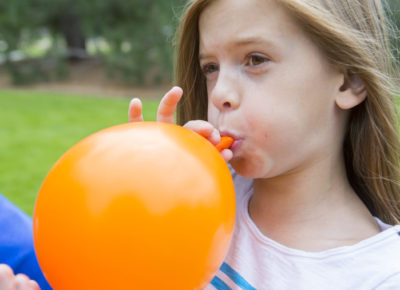 girl blowing up balloon to play Valentine's Day game: balloon buddies