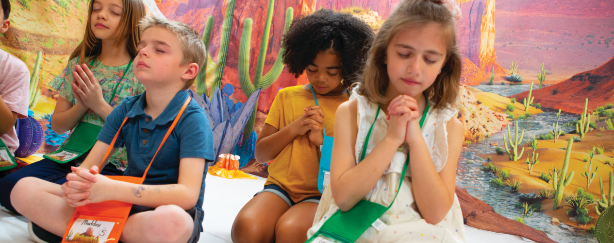 elementary kids praying at vbs monumental