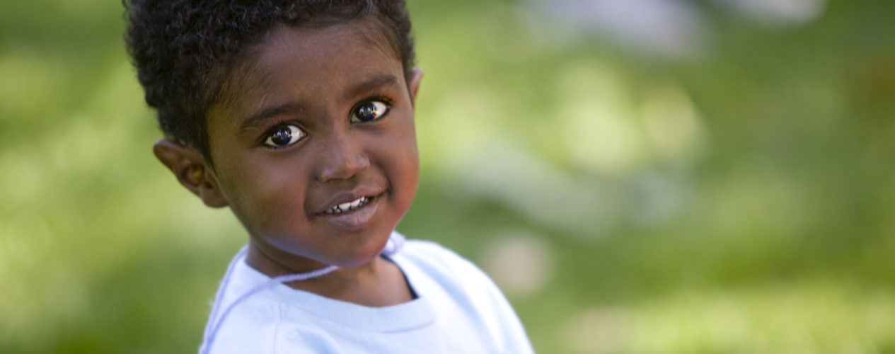 boy in blue shirt outside in grass