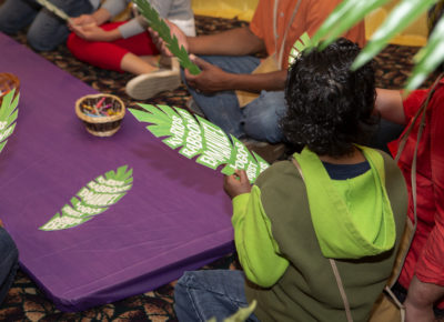 kids holding palm leaves and using them for craft