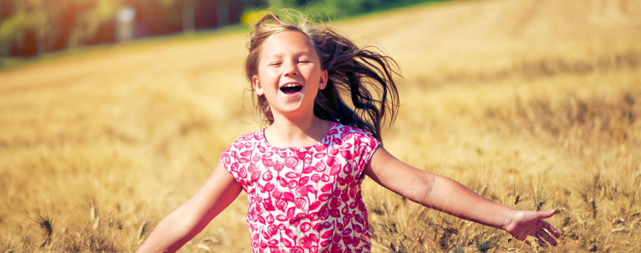 elementary aged girl smiling and running through field