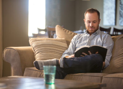 man sitting on couch reading the Bible