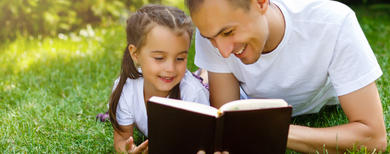 a dad and daughter outside reading the Bible