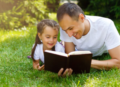 a dad and daughter outside reading the Bible