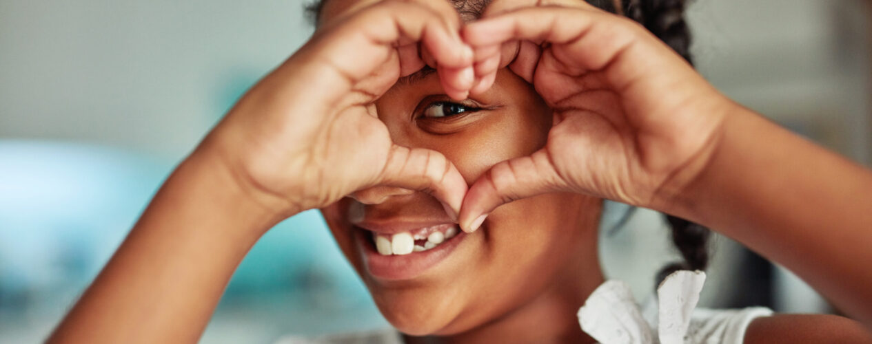 a girl smiling and making a heart with her hands