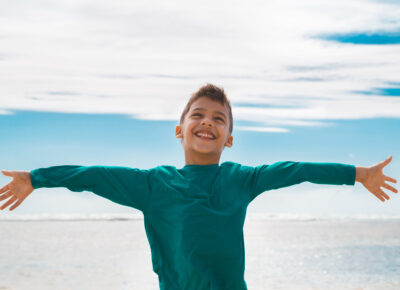 boy stretching out arms on beach