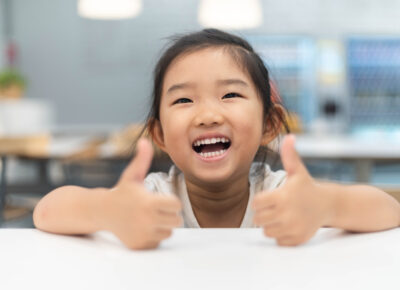 preschool girl smiling and giving thumbs-up