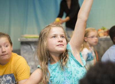 girl raising hand during children's devotion