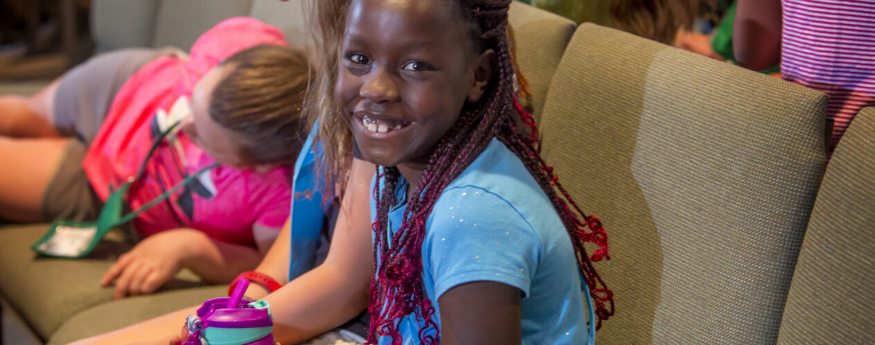 Elementary girl smiles as she participates in an object lesson about kindness—a fruit of the Spirit.