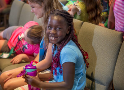 Elementary girl smiles as she participates in an object lesson about kindness—a fruit of the Spirit.