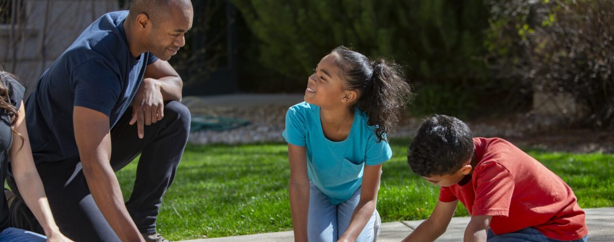 Parent and children play together outside.