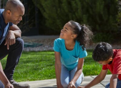Parent and children play together outside.