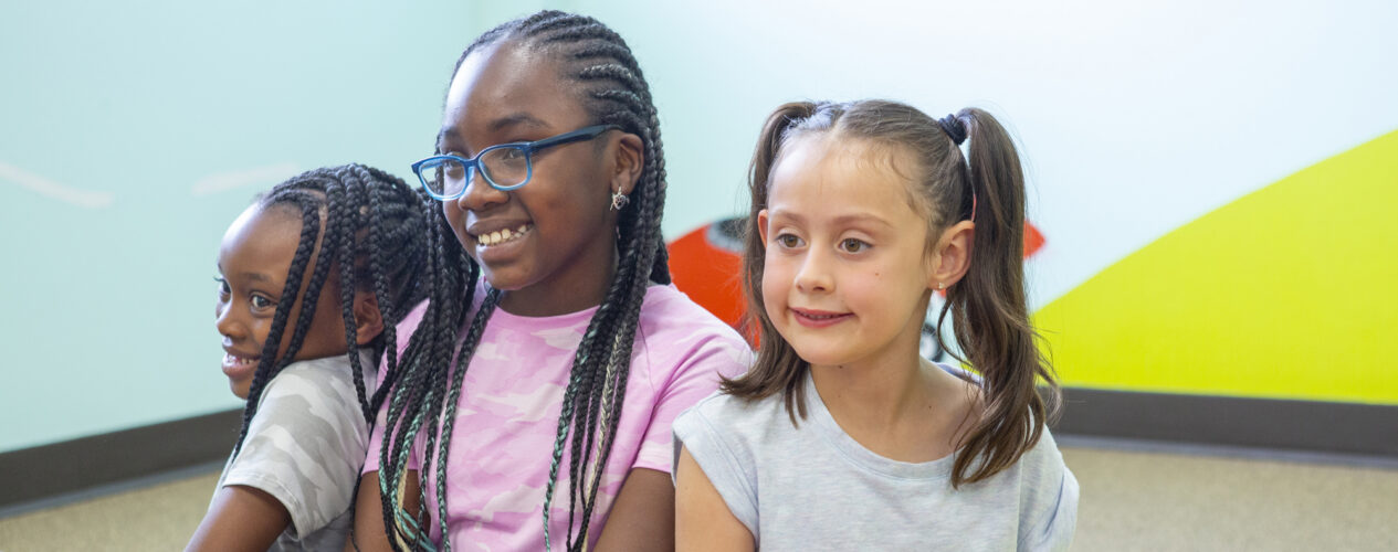 3 elementary or preteen age girls smile as they listen to a Sunday school lesson.