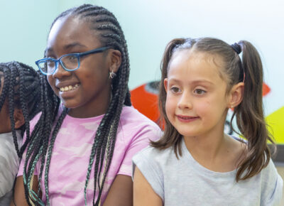 3 elementary or preteen age girls smile as they listen to a Sunday school lesson.